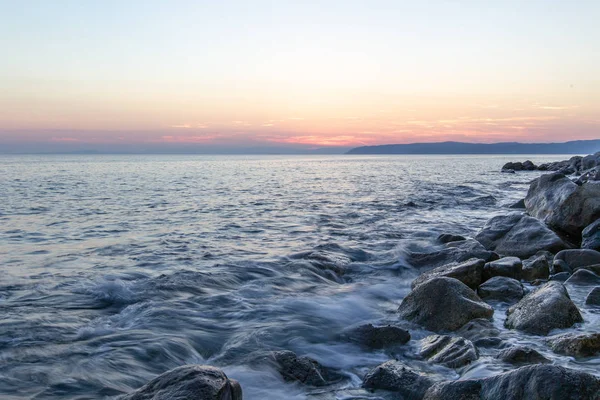 Deniz dalgası, Holy Mount Athos sahilinin yakınında gün batımında taşlar vurur