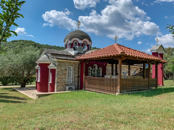 Una pequeña iglesia en el Monte Athos con paredes rojas, azulejos con un baptisterio y una campana —  Fotos de Stock