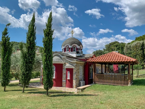 Маленькая церковь на горе Афон с красными стенами, выложенными плиткой с баптистерией и колоколом — стоковое фото