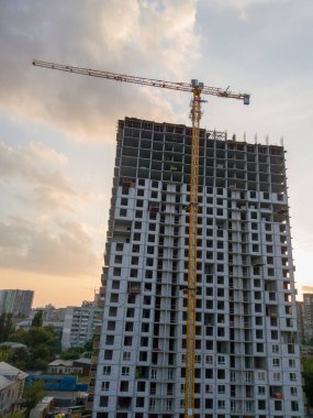 Gün batımında vinçle inşaat aşamasında olan bir binanın silueti