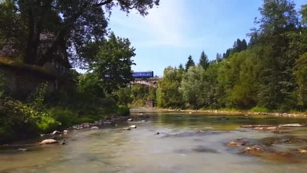 火车穿过山上的一块石头，一条浅河，在喀尔巴鄂山脉有湍急的水流，在阳光明媚的日子里有岩石底部。4k 拍摄 — 图库视频影像