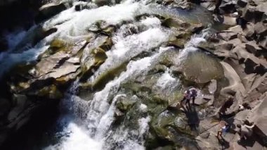 Taşlar arasında su akıntısı akar. Berrak su hızla karanlık ıslak taşlar etrafında akan yokuş aşağı düşmek. Siyah kayalarakan şelalenin yakın çekim. Güzel dağ şelalesi