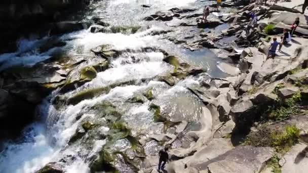 水流在石头之间流动。清澈的水迅速下坡，在暗湿的石头上流淌。瀑布倾泻而下黑岩石的特写镜头。美丽的山瀑布 — 图库视频影像