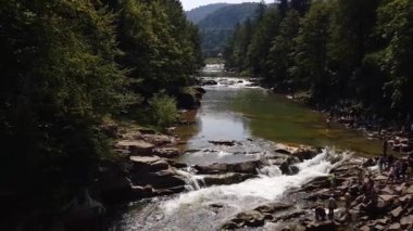 Taşlar arasında su akıntısı akar. Berrak su hızla karanlık ıslak taşlar etrafında akan yokuş aşağı düşmek. Siyah kayalarakan şelalenin yakın çekim. Güzel dağ şelalesi