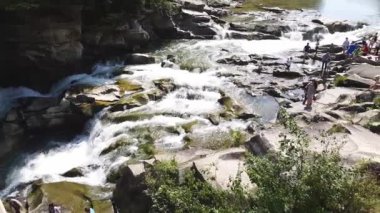 Taşlar arasında su akıntısı akar. Berrak su hızla karanlık ıslak taşlar etrafında akan yokuş aşağı düşmek. Siyah kayalarakan şelalenin yakın çekim. Güzel dağ şelalesi