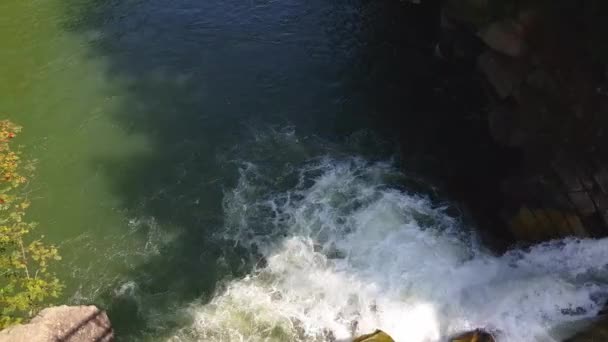 Water stroom stroomt tussen stenen. Helder water valt snel bergafwaarts en stroomt rond donkere natte stenen. Close-up van waterval gieten zwarte rotsen. Prachtige berg waterval — Stockvideo