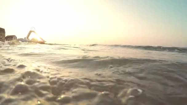 Sunrise by the sea. Catamaran stands on the beach by the sea. Sandy beach washed by the sea waves on a summer morning. — Stock Video
