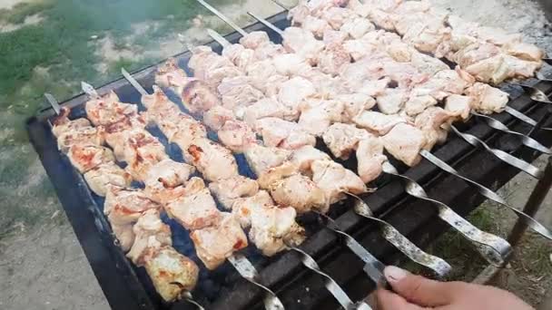 Le mani di un uomo ruotano gli spiedini. Shish kebab. Pezzi di carne di maiale o di agnello che vengono fritti su una griglia di carbone. Friggere pezzi di carne alla griglia durante il resto. — Video Stock