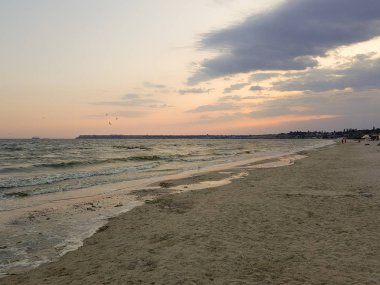Alacakaranlık ta gün batımından sonra plaj. Kumda güzel desenlerle plajdan denize akan su.