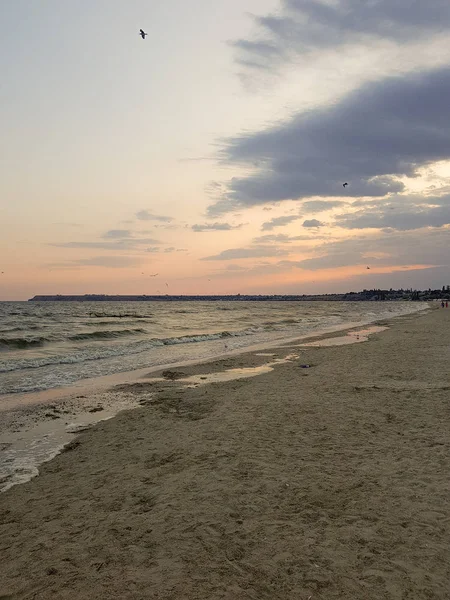 Alacakaranlık ta gün batımından sonra plaj. Kumda güzel desenlerle plajdan denize akan su. — Stok fotoğraf