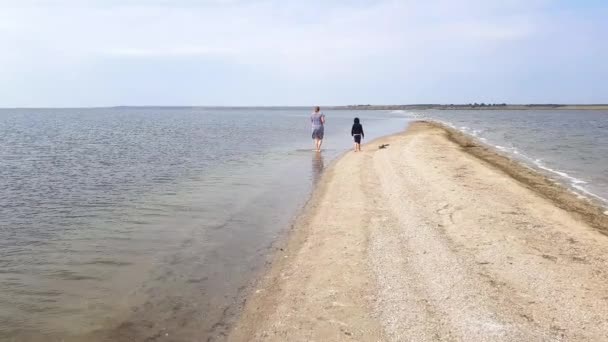 Beautiful view of family walking along spit. Mom and little daughter walk on the spit in early autumn — Stock Video