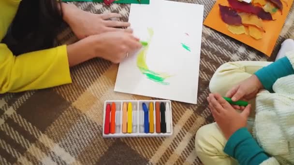 Młoda matka i córka rysować pastele olejne napis Jesień na białych arkuszach papieru i zrobić aplikację. Mała dziewczynka z mamą rysować napis olejny Jesienny napis na białej kartce papieru. — Wideo stockowe