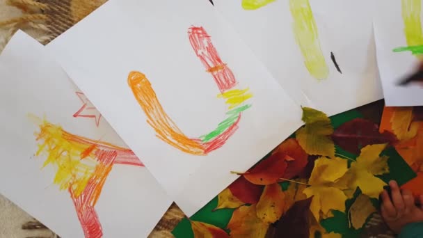 Genç anne ve kız yağ rengi pastel yazılar çiziyor. Beyaz kağıtlara sonbahar yazılıyor ve başvuru yapılıyor. Annesi olan küçük bir kız, beyaz kağıt üzerine sonbahar yazıtları çiziyor.. — Stok video