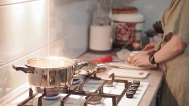 Mutfakta fırında çorba pişiren güzel bir kadın. Ev hanımı evde yemek hazırlıyor. Genç bir kadın modern mutfakta kaşık üstüne çorba tadıyor..