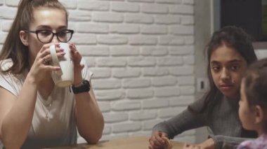 Annelik, ebeveynlik, aile, beslenme konsepti - Orta Doğu 'nun genç, sevimli, iri yarı, çocuklu annesi evde mutfakta yemek yiyor..