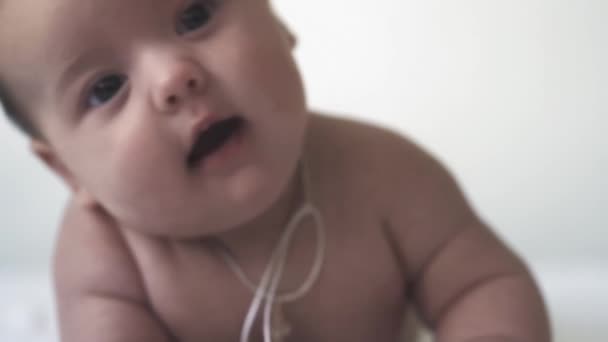 Säugling, Entwicklung, Kindheit, Ausbildung, Pädiatrie, Medizin und Gesundheitskonzept - Nacktes Neugeborenes liegt in Nahaufnahme auf dem Bauch und versucht, den Kopf auf weißem Hintergrund zu heben und zu halten. — Stockvideo