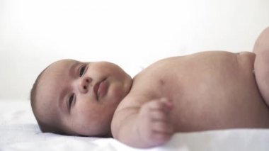 Bebek, gelişim, çocukluk, eğitim, pediatri, tıp ve sağlık konsepti - yakın plan çıplak bebek beyaz arka planda farklı ekşimeler ve duygular göstererek yatakta yatar