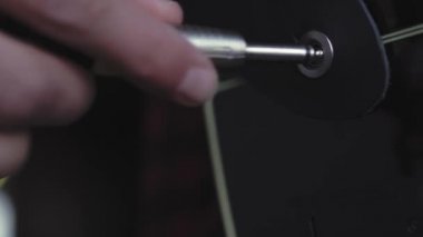 Müzik, yaratıcılık, konser, kendini izole etme konsepti. Akustik gitar çalan genç adamın yakın çekim elleri hafif odaklı. Gitarist sağ el, prizi soket müzik aletine takıyor..