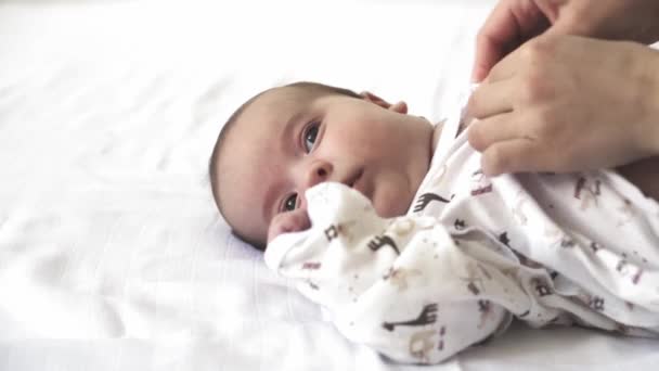Nourrissons, maternité, développement, enfance, formation, pédiatrie, médecine et santé concept - gros plan nouveau-né nu mensonges réveille maman met bébé en body. sur fond blanc . — Video