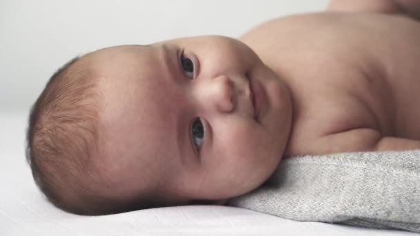 Bayi, perkembangan, masa kanak-kanak, pelatihan, pediatri, kedokteran, dan konsep kesehatan - bayi yang baru lahir telanjang bangun di tempat tidur menunjukkan grimm dan emosi yang berbeda dengan latar belakang putih — Stok Video