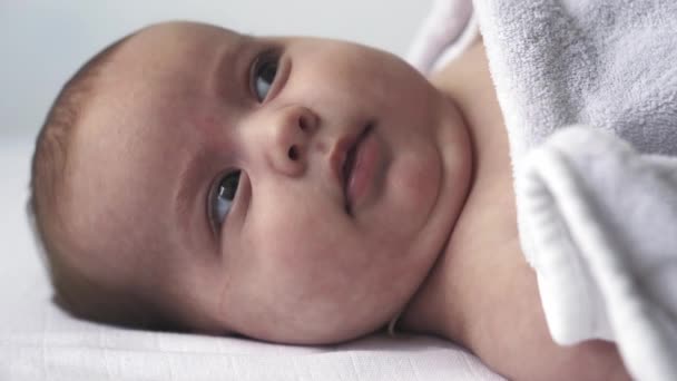 Baby, ontwikkeling, kindertijd, training, kindergeneeskunde, geneeskunde en gezondheid concept - close-up naakt pasgeboren baby ligt wakker op bed met verschillende grillen en emoties op witte achtergrond — Stockvideo