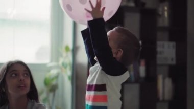 Çocuklar, kutlama, doğum günü, büyük aileler, oyunlar ve eğlence konsepti - farklı yaş ve milletten çocuklar ve gençler pencerenin önündeki geniş odada balonlarla oynuyorlar..