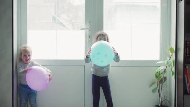Děti, oslavy, narozeniny, velké rodiny, hry a zábavní koncept - malé děti a dospívající různého věku a národnosti si hrají s balónky v prostorné místnosti u okna. — Stock video