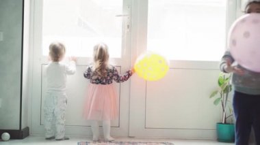 Çocuklar, kutlama, doğum günü, büyük aileler, oyunlar ve eğlence konsepti - farklı yaş ve milletten çocuklar ve gençler pencerenin önündeki geniş odada balonlarla oynuyorlar..