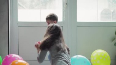 Çocuklar, kutlama, doğum günü, büyük aileler, oyunlar ve eğlence konsepti - farklı yaş ve milletten çocuklar ve gençler pencerenin önündeki geniş odada balonlarla oynuyorlar..