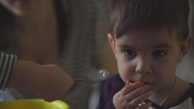 Annelik, çocukluk, beslenme, yemek, aile, bakım konsepti - bebek elinin yakınlığı Orta Doğulu iki yaşındaki çocuğunu kaşıkla besliyor anne yerde otururken alkışlıyor