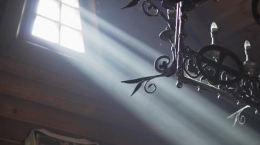 Din, bayramlar, konsept - Hıristiyan Ortodoks tapınağındaki sunak tahtına düşen dumanlı odadaki pencereden gelen ışık ışınları yanında şamdan yakan şamdanla avize altında.