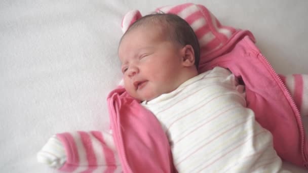 Säugling, Kindheit, Mutterschaft, Familie, Thygiene, Medizin und Gesundheitskonzept - Nahaufnahme Frauenhände kleiden neugeborenes waches Baby in rosa Bluse Draufsicht auf weißem Hintergrund in den ersten Minuten des Lebens — Stockvideo