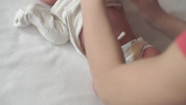 Baby, kindertijd, moederschap, familie, thygiëne, geneeskunde en gezondheid concept - close-up mama handen uitkleedt neemt bodysuit pasgeboren wakker baby top uitzicht op witte achtergrond in de eerste minuten van het leven — Stockvideo