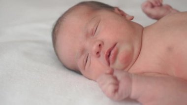 Bebeklik, çocukluk, tıp ve sağlık, pediatri konsepti - hayatın ilk dakikalarında çıplak bebek sırtüstü yatar, döner ve ağlar doğal ışıkta beyaz bir yatakta..