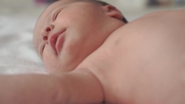 bebeklik, çocukluk, gelişim, tıp ve sağlık konsepti - yeni doğmuş çıplak yüzün yakın çekimi sakin uyanık bebek suratları sırt üstü uzanmış beyaz bej arka planda tıbbi klipslerle