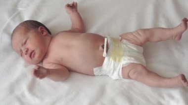 bebeklik, çocukluk, gelişim, tıp ve sağlık konsepti - yeni doğmuş çıplak, tatminsiz, göbek deliğinde beyaz bej arka planda tıbbi klipsle uzanan bebeğin yakın çekimi