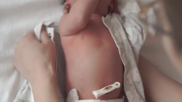 Kindertijd, kindertijd, moederschap, hygiëne, geneeskunde en gezondheid concept - vrouwelijke hand moeder op pasgeboren naakte baby liggend in luier op de rug met navel geknepen door medische clip op witte achtergrond. stap 2 — Stockvideo