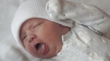 bebeklik, çocukluk, gelişim, tıp ve sağlık konsepti - bebek tulumu giymiş, beyaz bej arka planda sırtüstü uzanan bebek uykusundan uyanmış bebek için yakın çekim görüntüsü