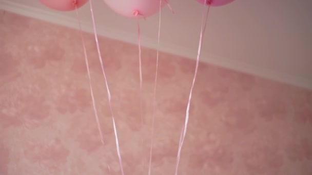 Bambini, festeggiamenti, compleanni, famiglie numerose, giochi e intrattenimento: Little Girl guarda fuori da dietro i palloncini e ride felicemente. Close up Ritratto di bambino che gioca su sfondo rosa — Video Stock