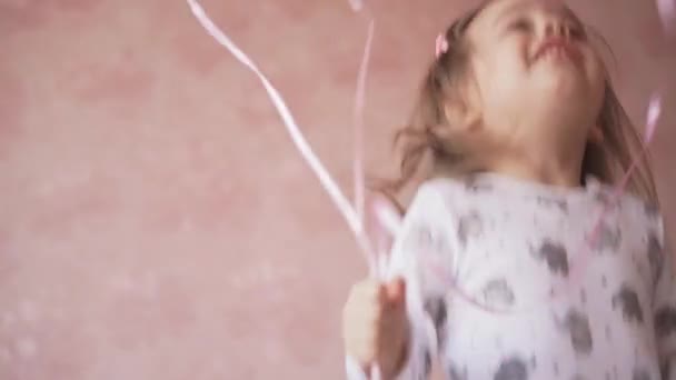 Bambini, festeggiamenti, compleanni, famiglie numerose, giochi e intrattenimento: Little Girl guarda fuori da dietro i palloncini e ride felicemente. Close up Ritratto di bambino che gioca su sfondo rosa — Video Stock