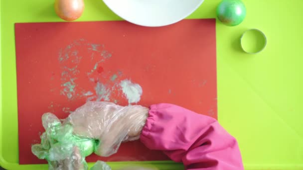 Velikonoce, Velikonoce, dětství, kreativita, koncept hry - detailní záběr malé roztomilé blond tříleté dívky slovinského bělocha v růžových županových barvách Velikonoční vajíčka v plastových rukavicích. — Stock video