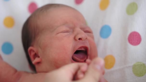 Kindertijd, kindertijd, geneeskunde en gezondheid, kindergeneeskunde concept - close-up vrouwen hand en naakte pasgeboren baby in de eerste minuten van het leven liggend op de rug gooien en draaien en huilen in medisch glazen wieg. — Stockvideo