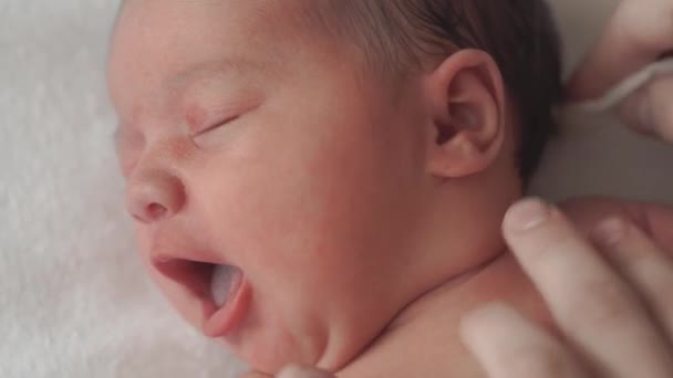 Infância, infância, maternidade, higiene, medicina e conceito de saúde - as mães do sexo feminino mão limpa o pescoço do bebê recém-nascido nu com algodão almofada deitada em fralda nas costas com o umbigo preso por clipe médico — Vídeo de Stock