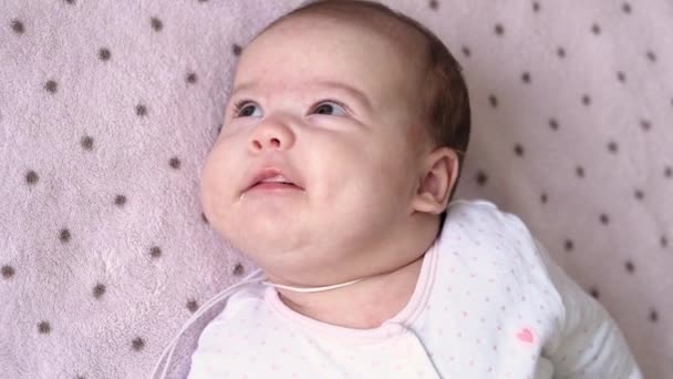 Bayi, masa kecil, perkembangan, obat-obatan dan konsep kesehatan pandangan close-up dari atas wajah bayi yang gemuk dan baru lahir tenang terjaga bayi berpakaian putih bodysuit senyum grimaces berbaring di belakang pada latar belakang merah muda — Stok Video