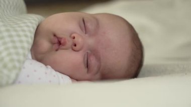 bebeklik, çocukluk, gelişim, tıp ve sağlık konsepti - yeni doğmuş tombul, uyuyan bebeğin yakın çekimi karın üstü uzanmış gözleri açık ve beyaz arka planda battaniyeyle kaplı gülümsemesi.