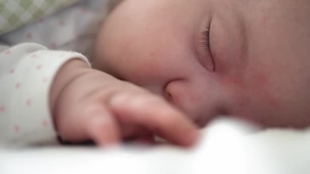 Kojenectví, dětství, vývoj, medicína a zdraví koncept - close-up tvář novorozence baculaté spící dítě dívka ležící na břiše otevřené oči a úsměv pokrytý přikrývkou na posteli na bílém pozadí. — Stock video