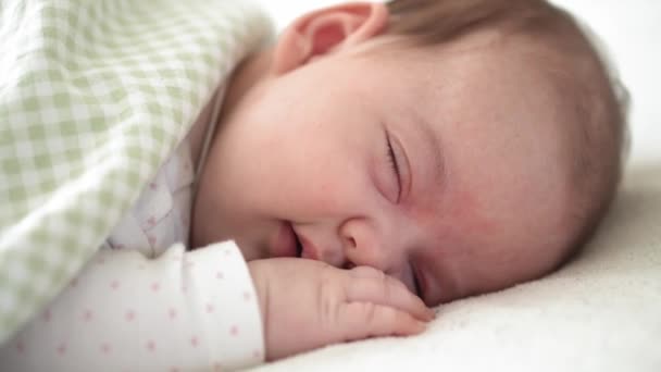 Infancia, infancia, desarrollo, medicina y concepto de salud: primer plano de la niña recién nacida gordita dormida acostada boca abajo con los ojos abiertos y sonrisa cubierta con manta en la cama sobre fondo blanco. — Vídeos de Stock