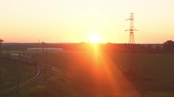 Vervoer, reizen, weg, spoorwegen, landschap, comnicatie concept - uitzicht vanaf het raam van de sneltrein met verblinding op glas en parallelle rails op het landschap van weiden en bossen voor zonsondergang in de zomer — Stockvideo