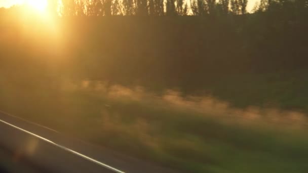 Doprava, cestování, silnice, železnice, krajina, koncept smilstva - pohled z okna rychlovlaku se záři na sklo a paralelní kolejnice na krajinu luk a lesů před západem slunce v létě — Stock video