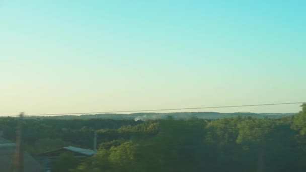 Doprava, cestování, silnice, železnice, krajina, koncept smilstva - pohled z okna rychlovlaku na krajinu krásného přírodního pole a lesa za jasného dne před západem slunce jasná obloha v létě — Stock video